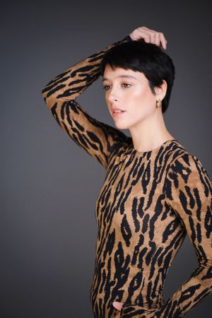 Stylish tiger print long sleeve top shown in fashion editorial against dark backdrop.