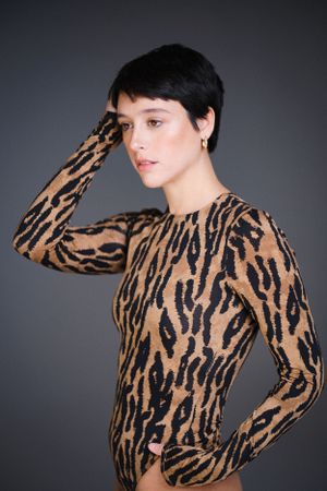 Fashion model showcases brown and black animal print top in studio photoshoot.