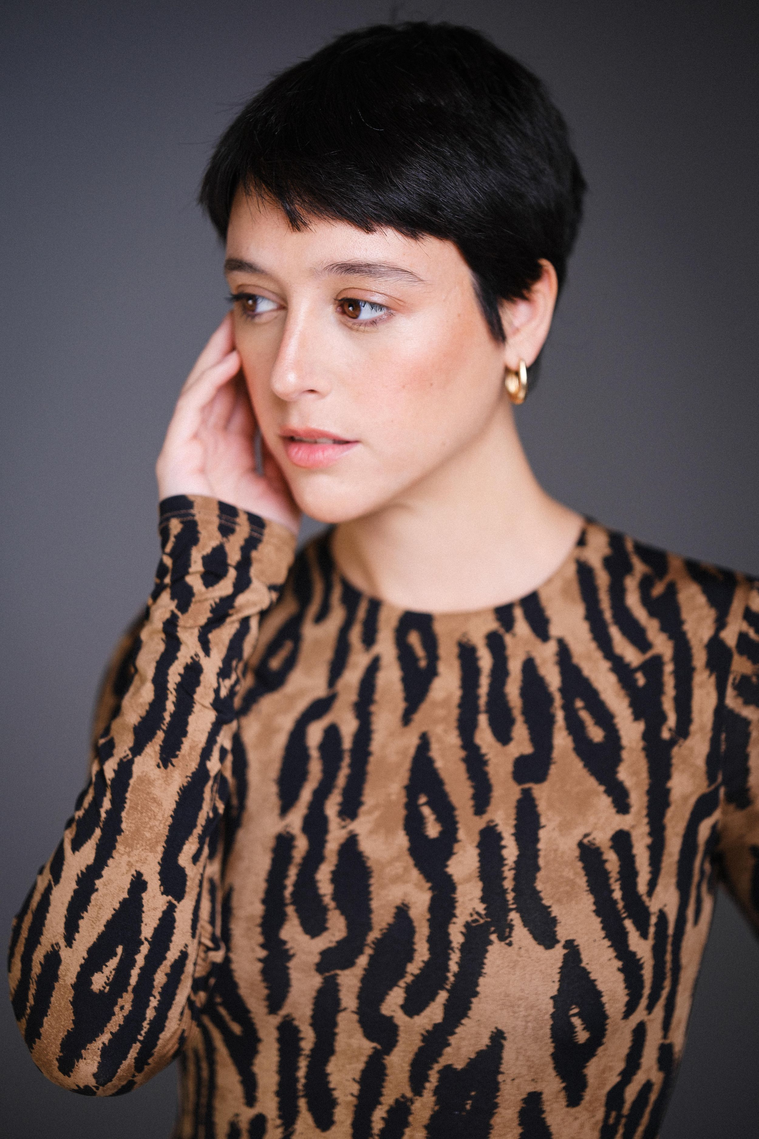 Editorial beauty shot featuring tiger print fashion piece in moody studio lighting.