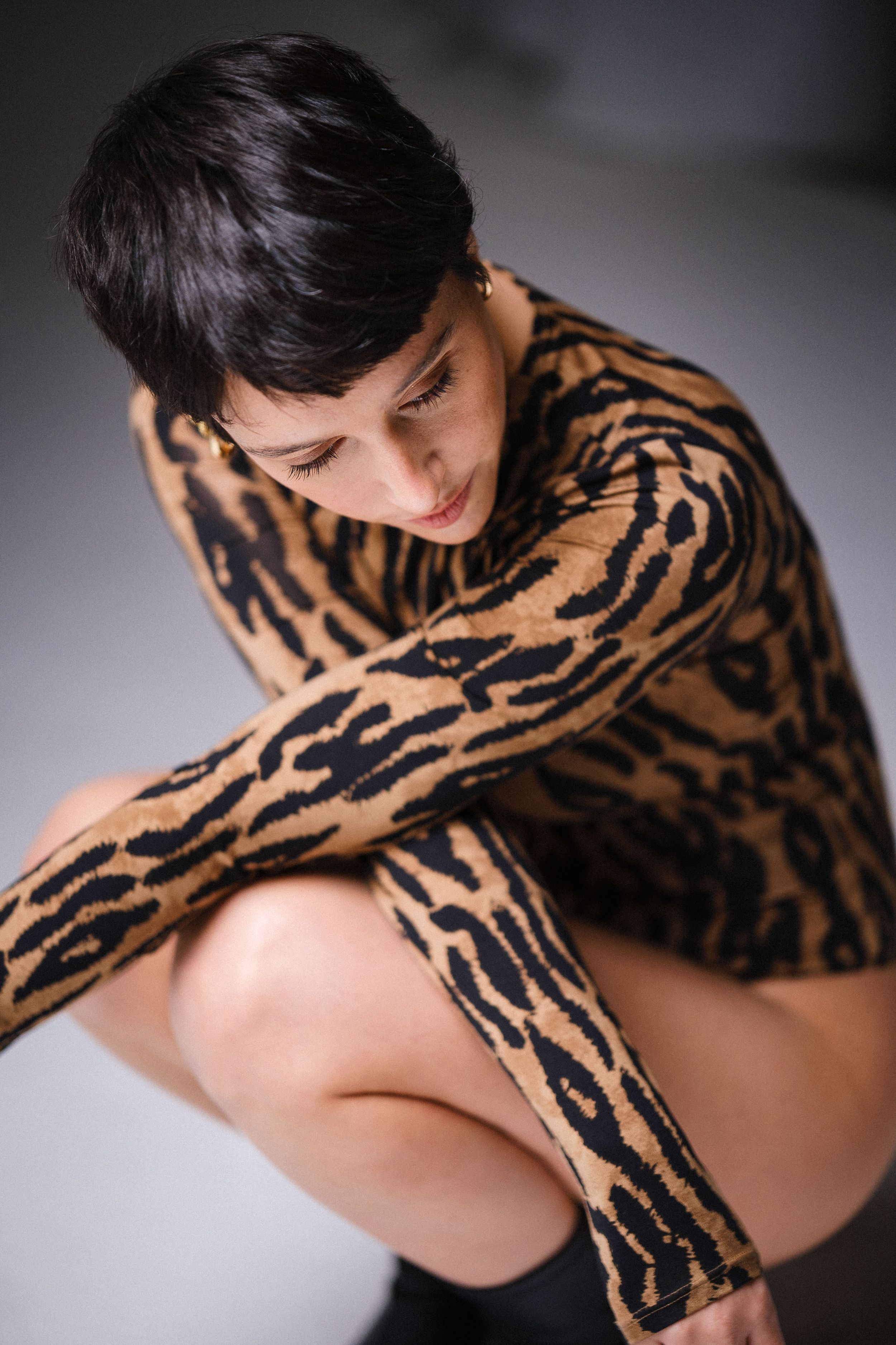 An artistic composition showing a tiger print garment in dramatic lighting.