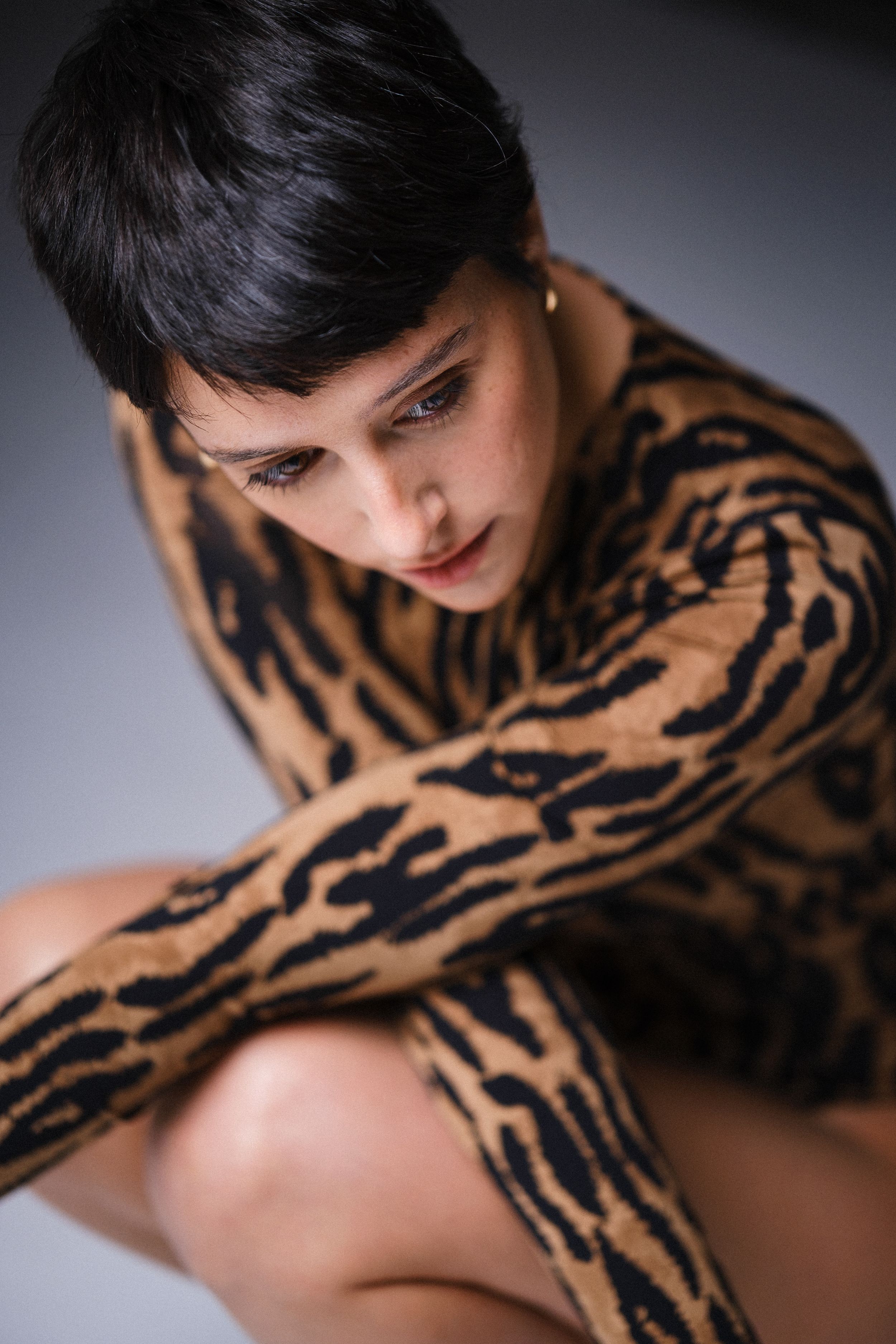 A moody studio portrait featuring a leopard print outfit against dark background.