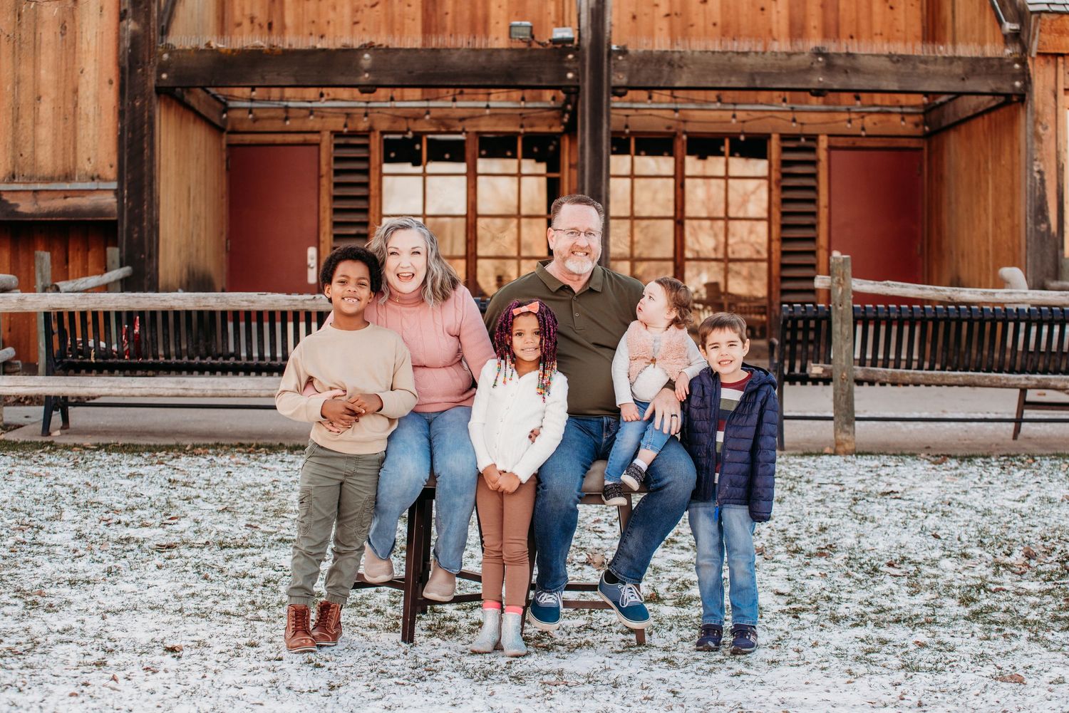 A family group posing together on a bench outside a rustic wooden building.