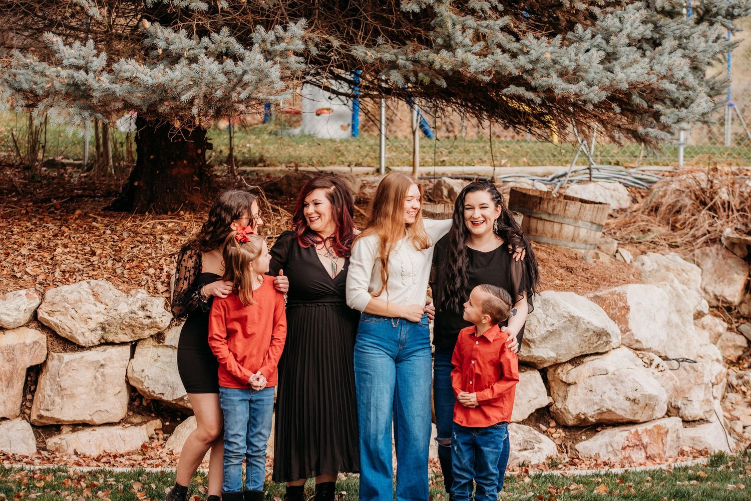 Family group portrait against rustic stone wall backdrop in casual attire.