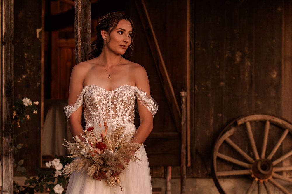 Elegant bridal portrait showing intricate lace details in a rustic barn setting with wagon wheel decor.