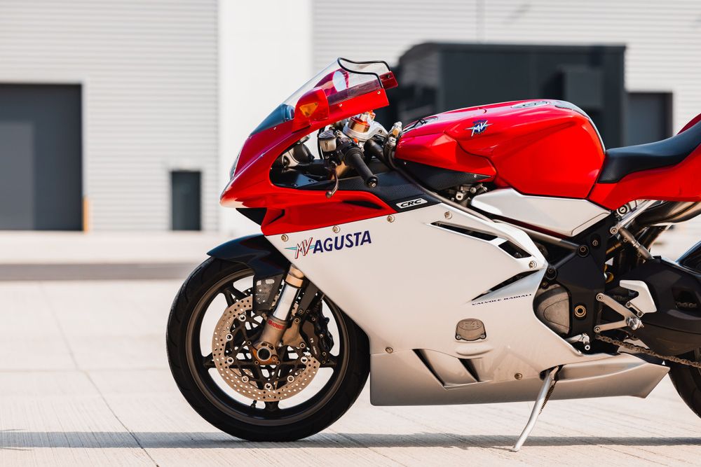 A red and white MV Agusta sport motorcycle parked against a modern building with white walls.