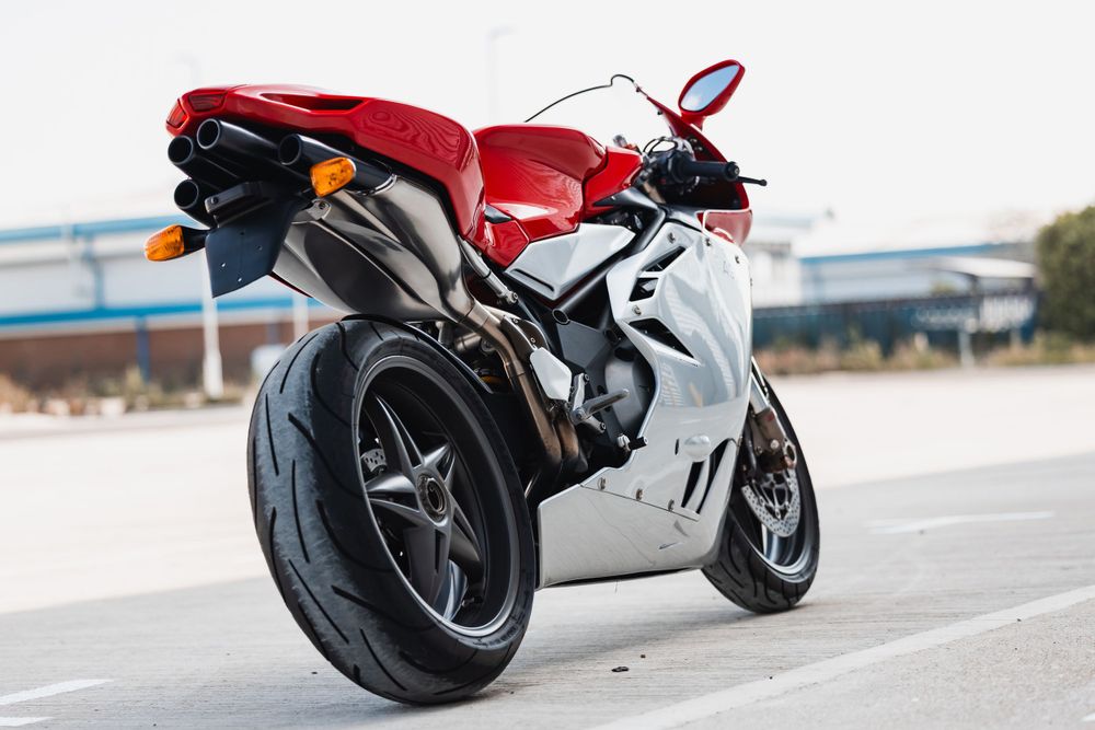 Red and white MV Agusta F4 superbike parked on street showcasing its sporty design and wide rear tire.