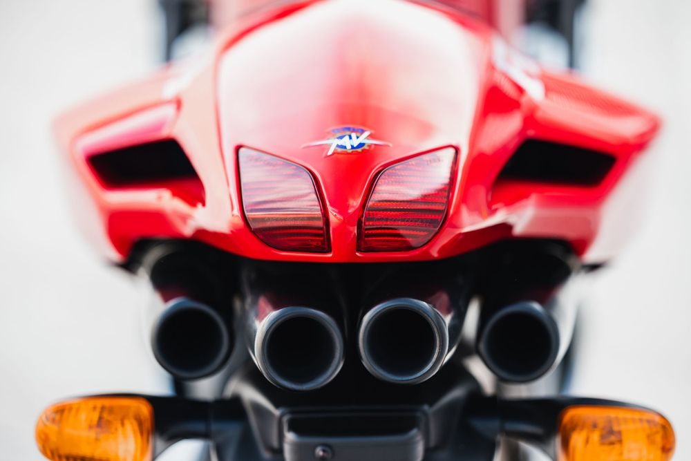 Close-up rear view of a red MV Agusta motorcycle showing quad exhaust pipes and taillight assembly.