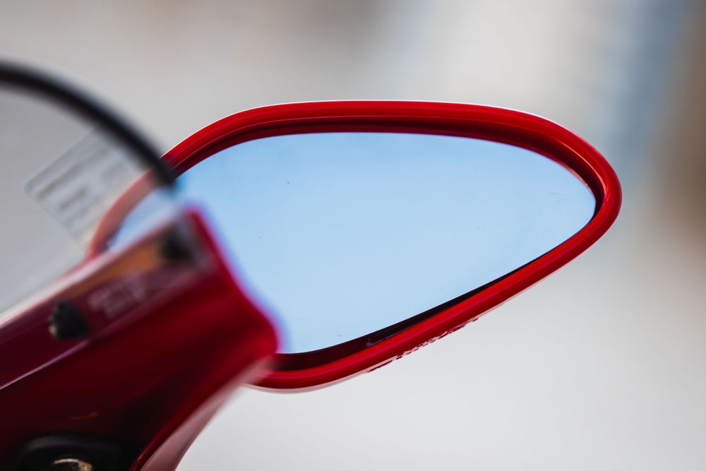 Close-up macro shot of a red-framed eyeglass lens showing curved edge detail and reflection.