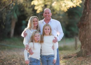Family portrait session in a sunlit forest with golden autumn colors.