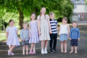 Group of small children walking and playing together outdoors on a sunny day.