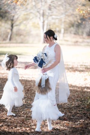 Little girls in white dresses twirling and playing in fallen autumn leaves.