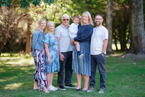 A family group poses together outdoors in coordinating blue and white outfits for a summer portrait session.