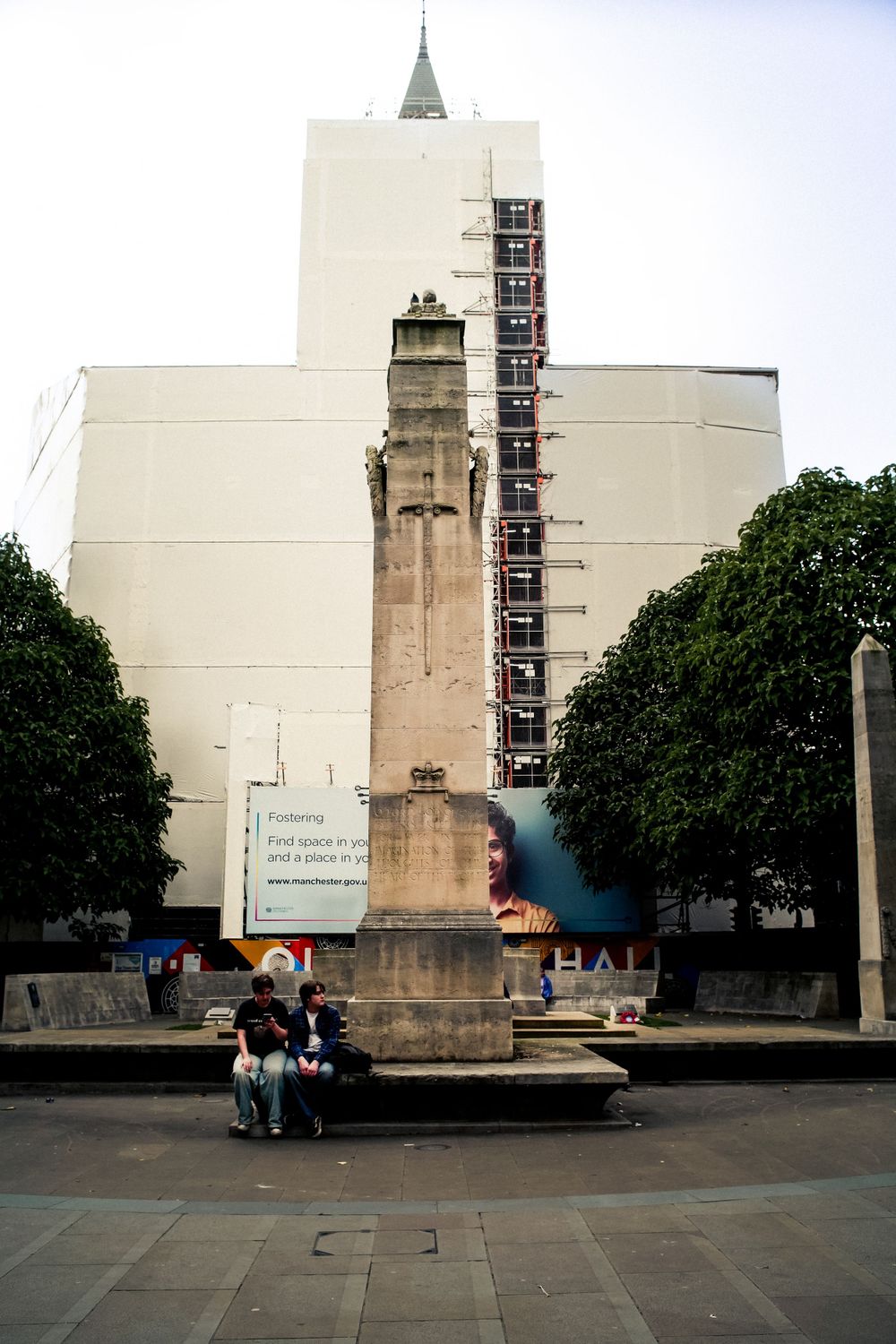 A tall white building with concrete monument and city square in the foreground.
