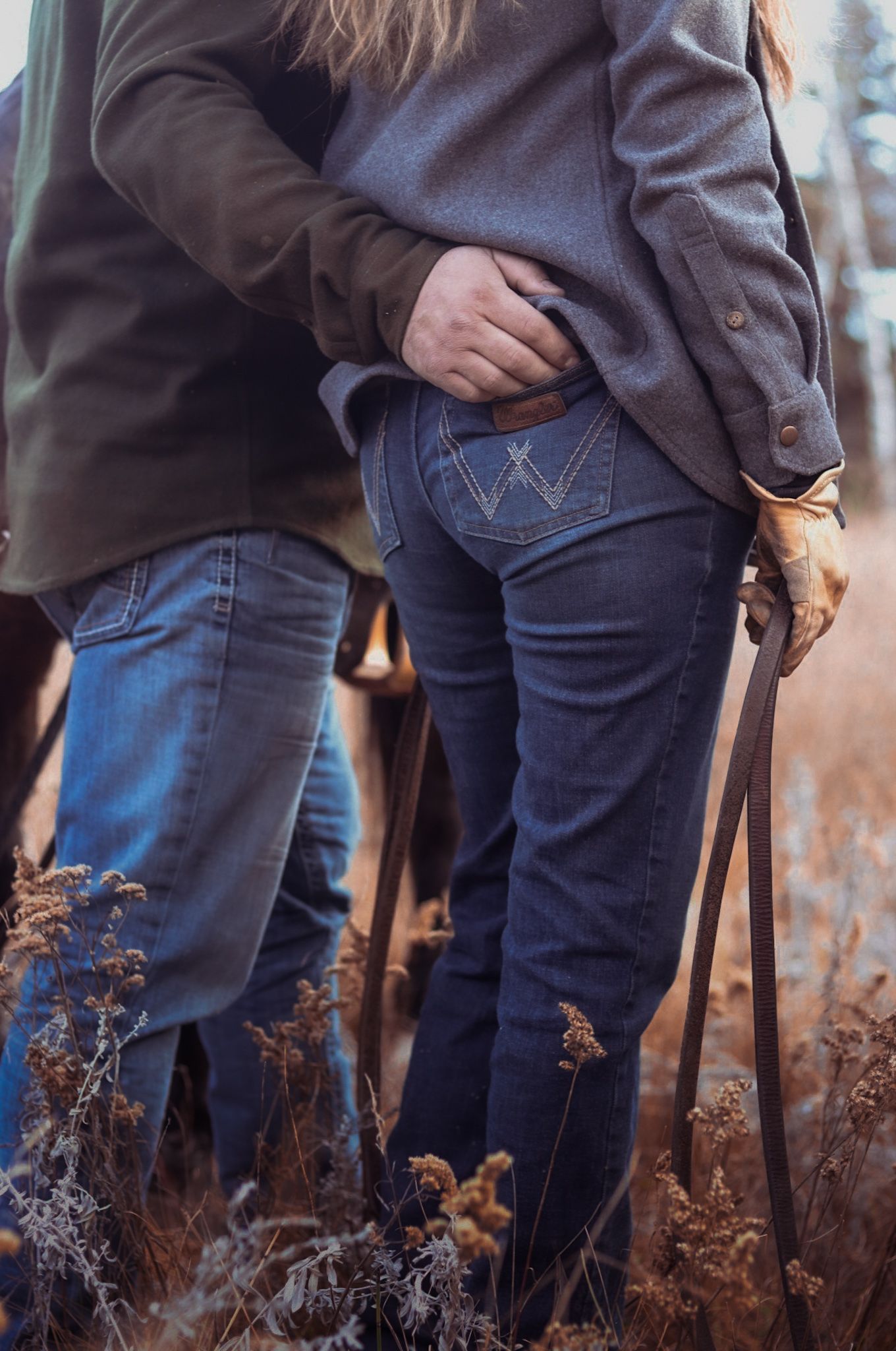 Detail shot of western-style jeans and boots while standing in tall dry grass.