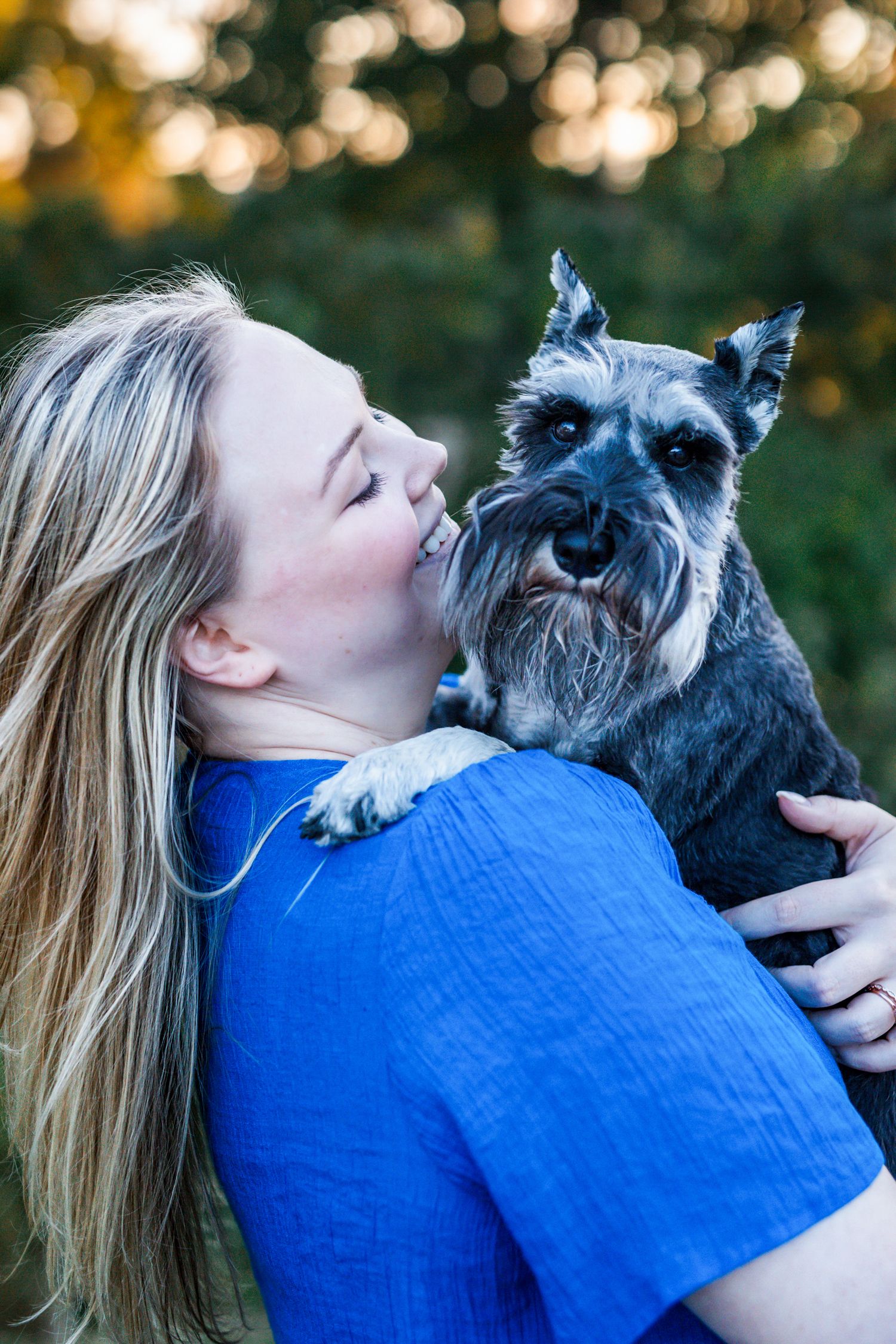 Woman and her dog share a warm moment at golden hour in a park, capturing their bond in soft natural light, Amherstburg Ontario.
