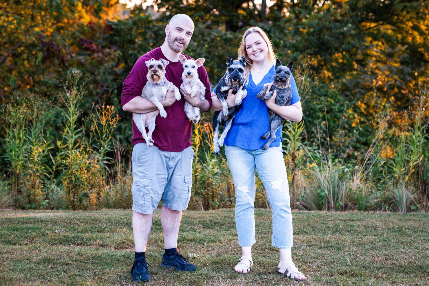 Husband and wife with their four dogs at golden hour in a Windsor Essex County park, capturing love and family togetherness.