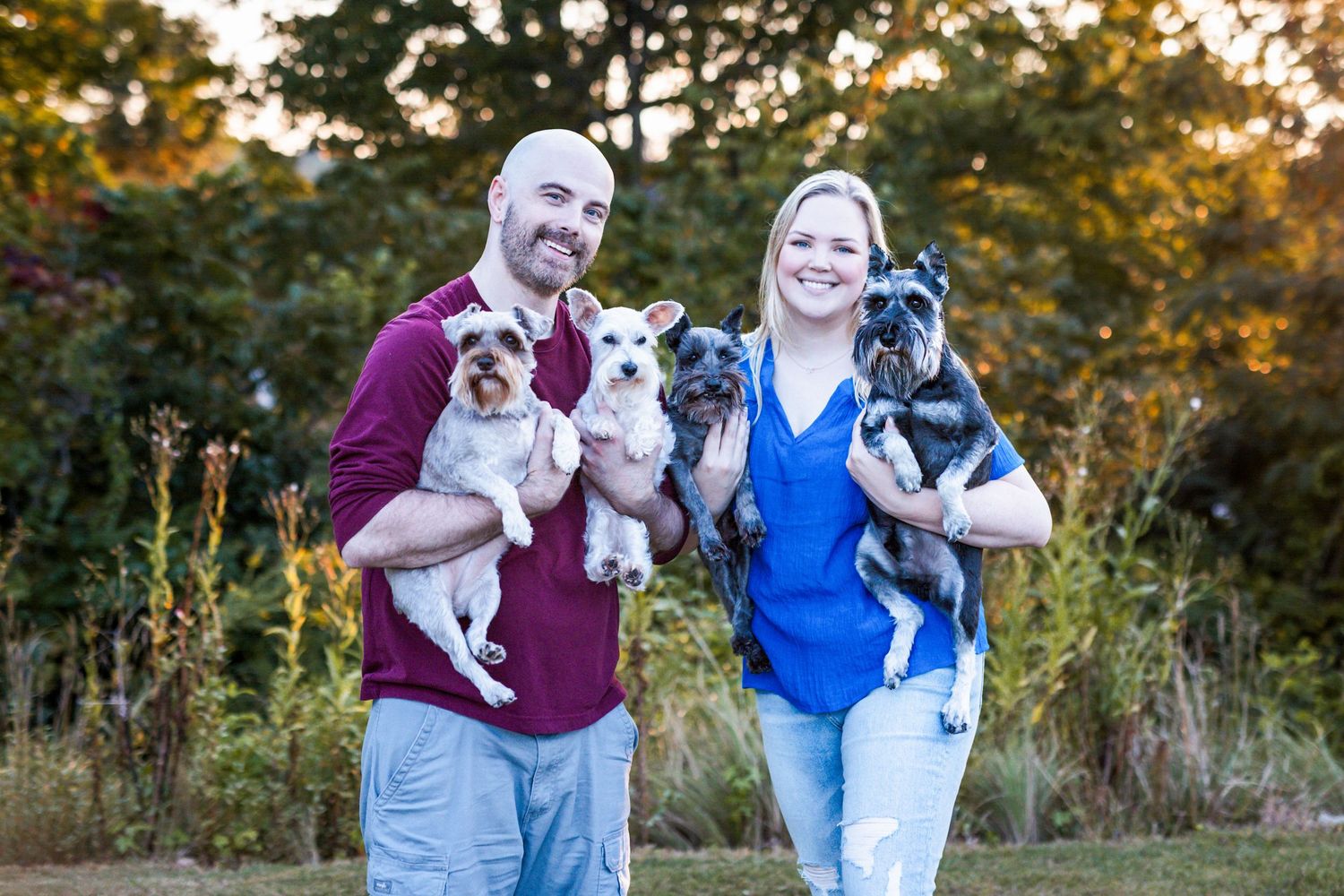 Outdoor family portrait of couple and four dogs at golden hour in Windsor Essex County park, warm light and joyful moments.