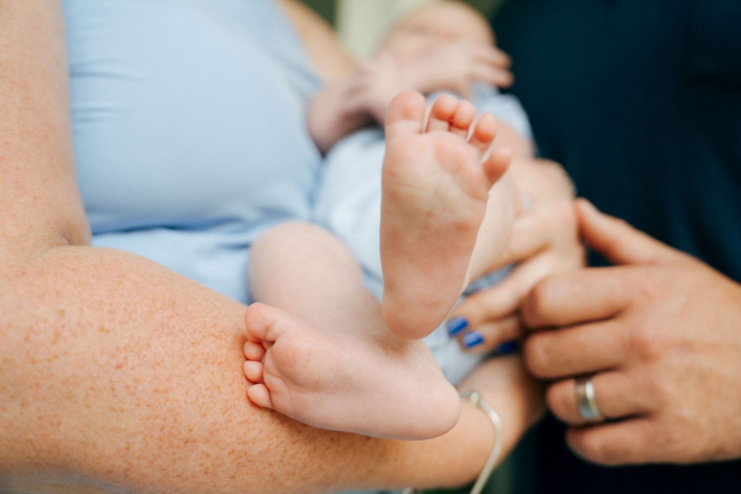 Close-up of tiny baby feet being held by gentle hands.