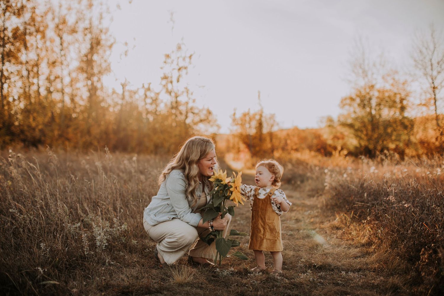 A tender autumn moment between parent and child on a rustic path at sunset.