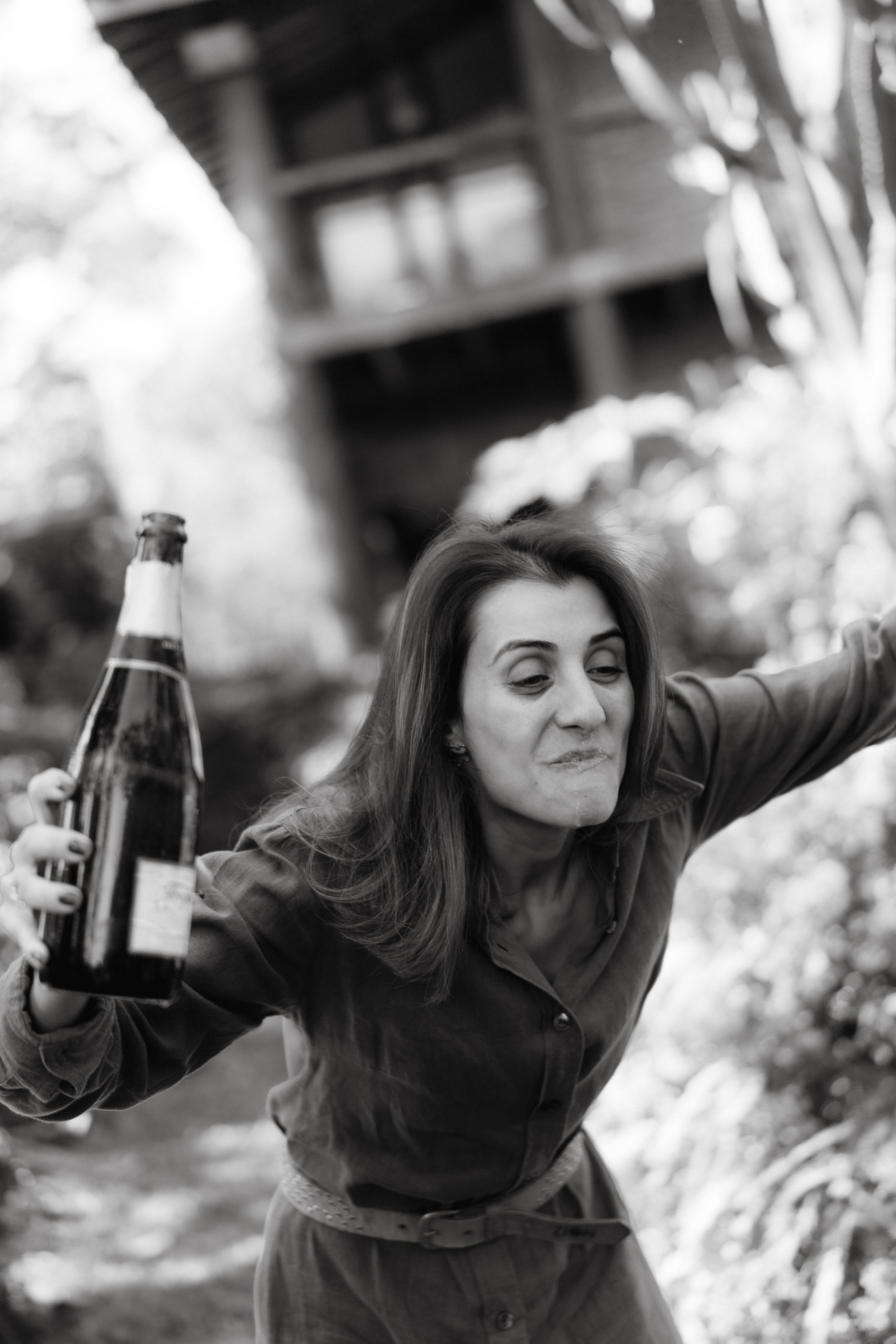 Black and white photo of someone playfully popping champagne outdoors.