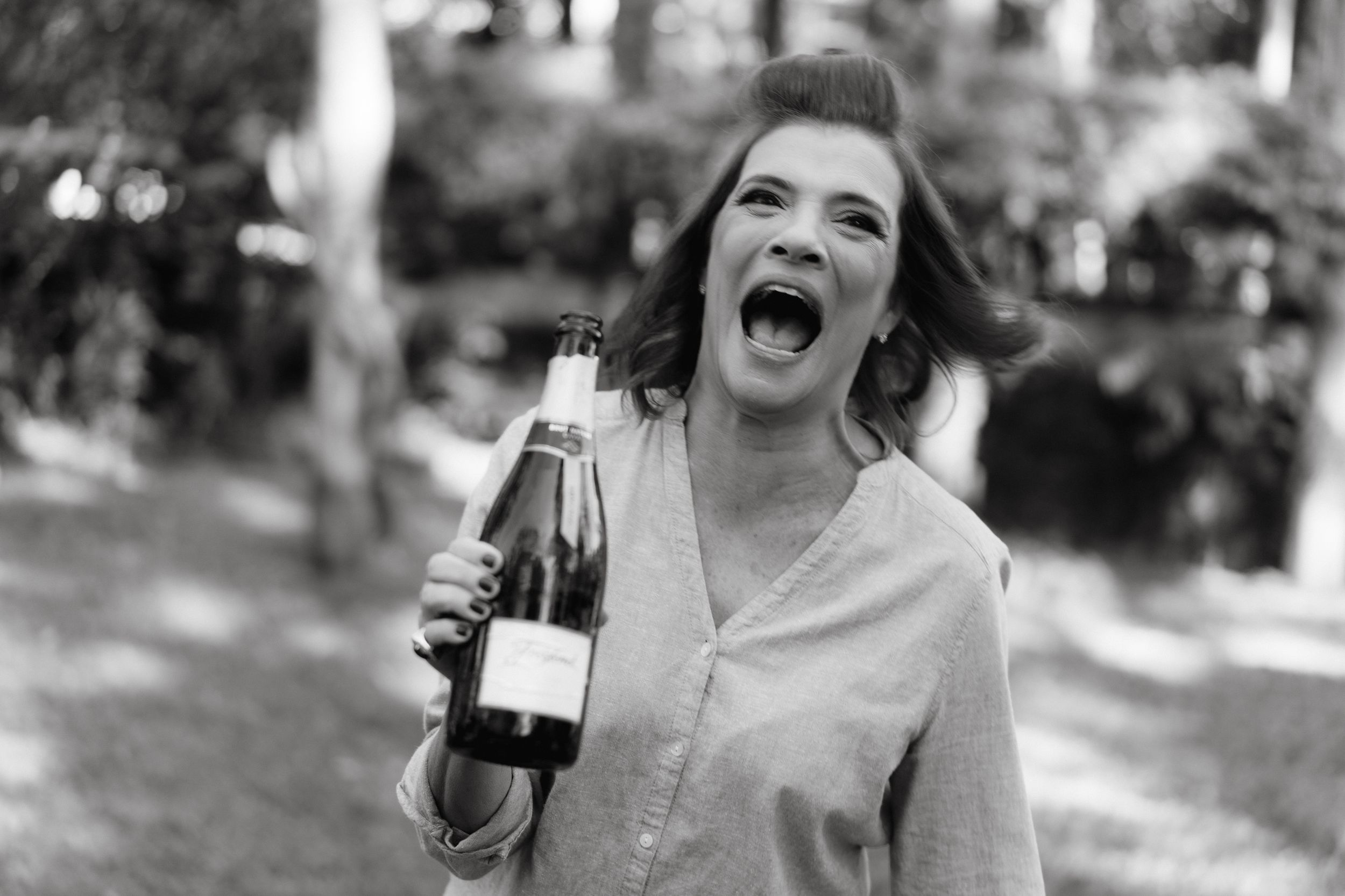 Someone celebrating with champagne bottles in a candid outdoor photoshoot.