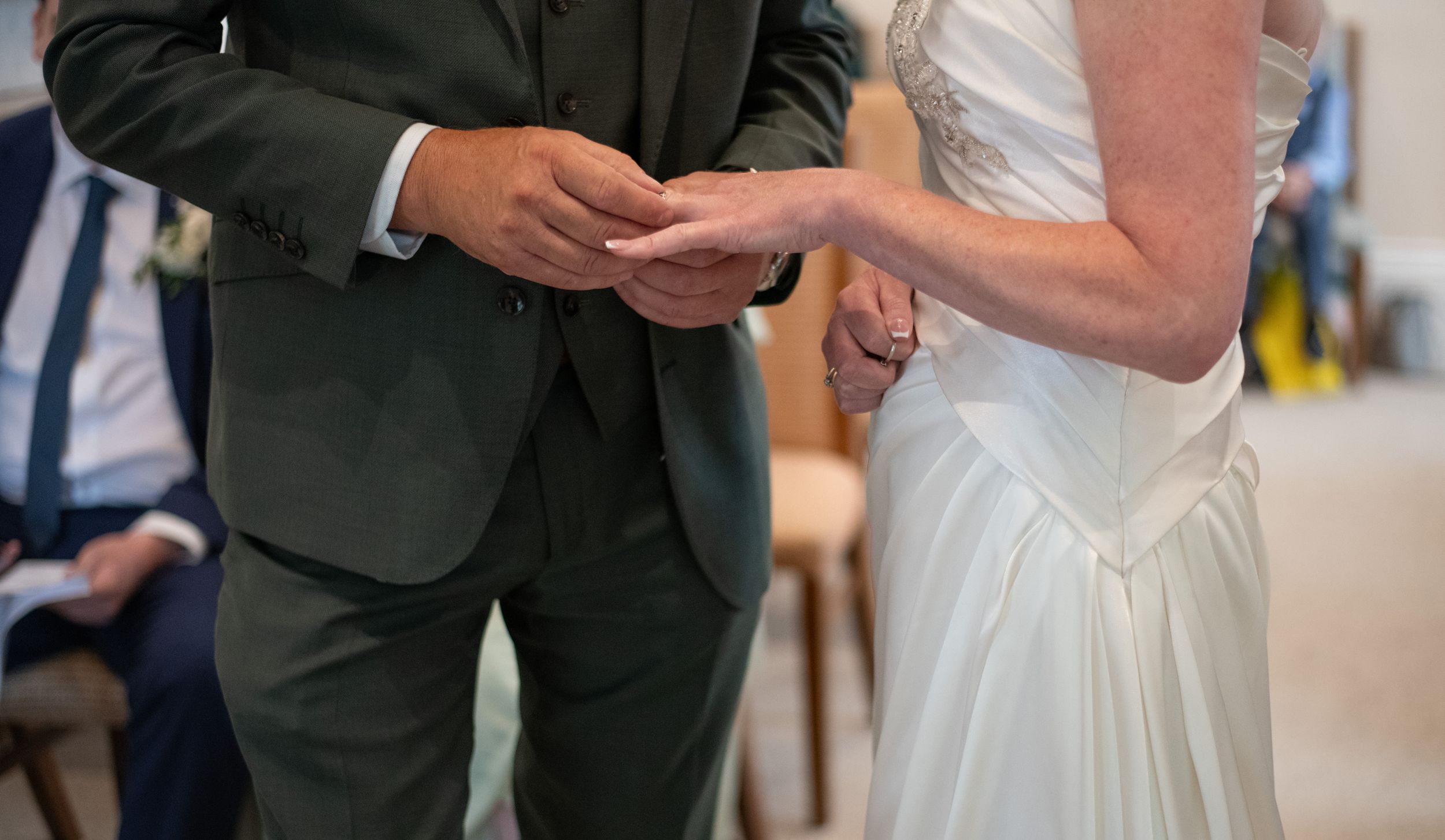 Close up of hands during ring exchange at wedding ceremony.