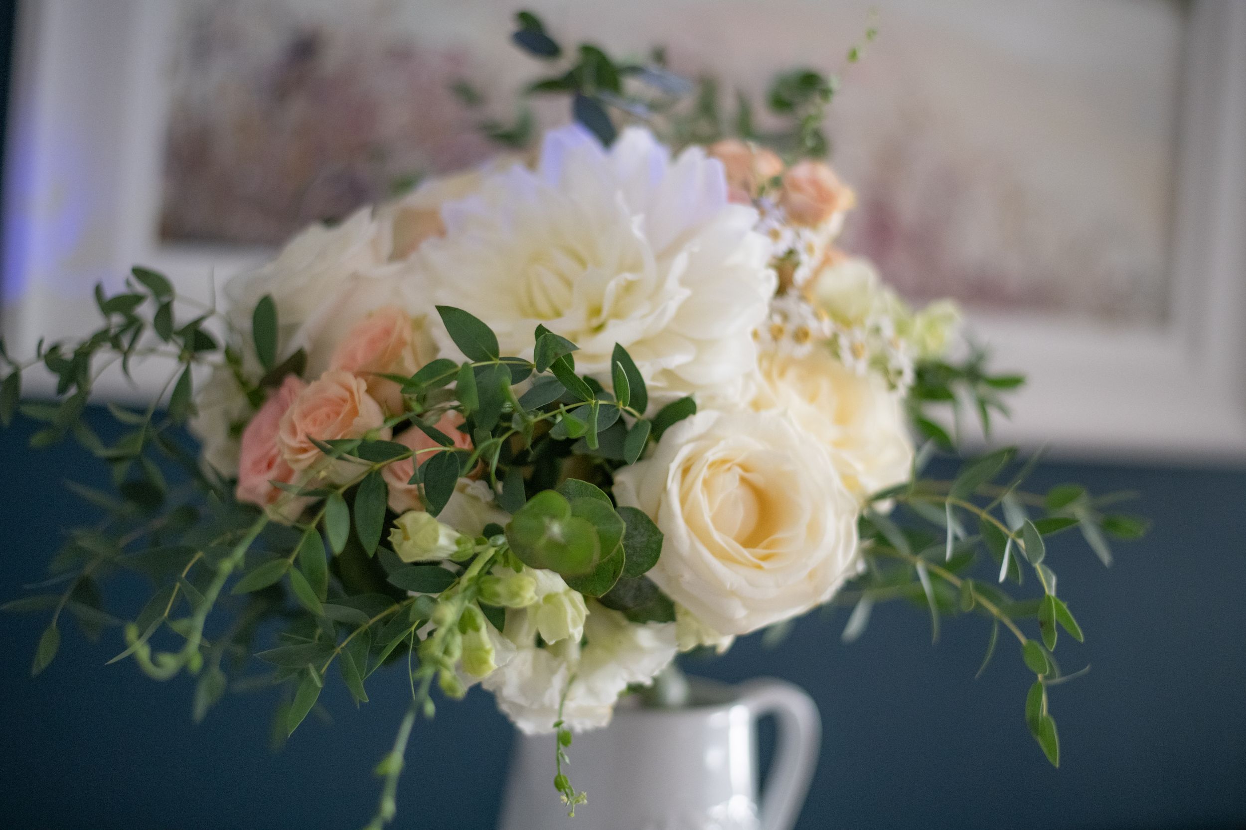 Elegant white and peach floral arrangement in a white vase.