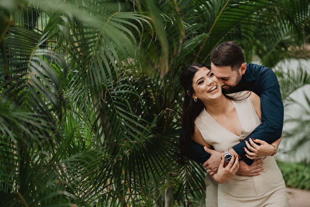Groom playfully hugging her, both having fun in a lighthearted moment on the shore