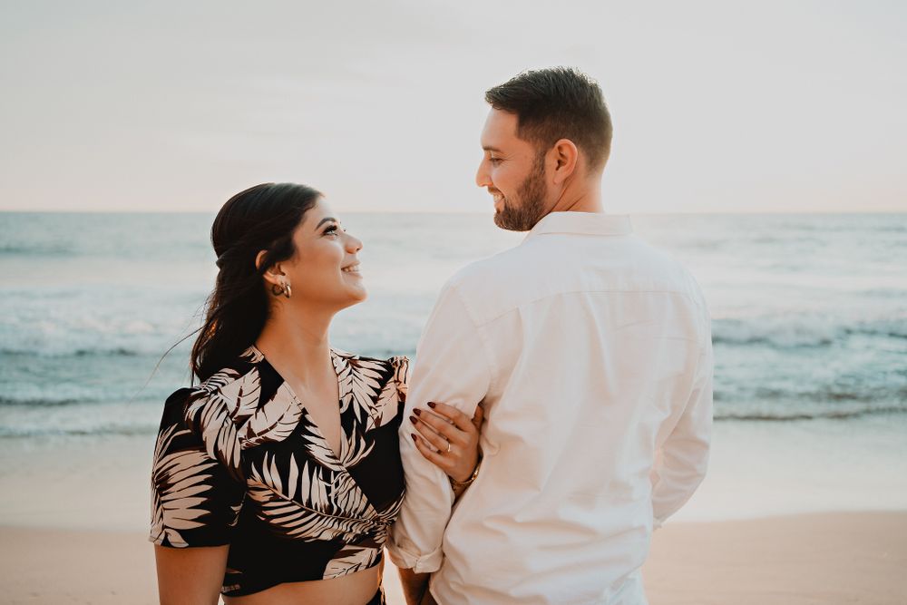 Romantic gaze between them, with the sea and sand of Mazatlán in the background