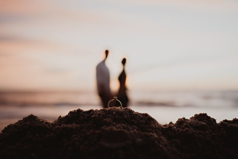 Ring in the sand, backlit by the ocean, with the couple's silhouettes representing their souls
