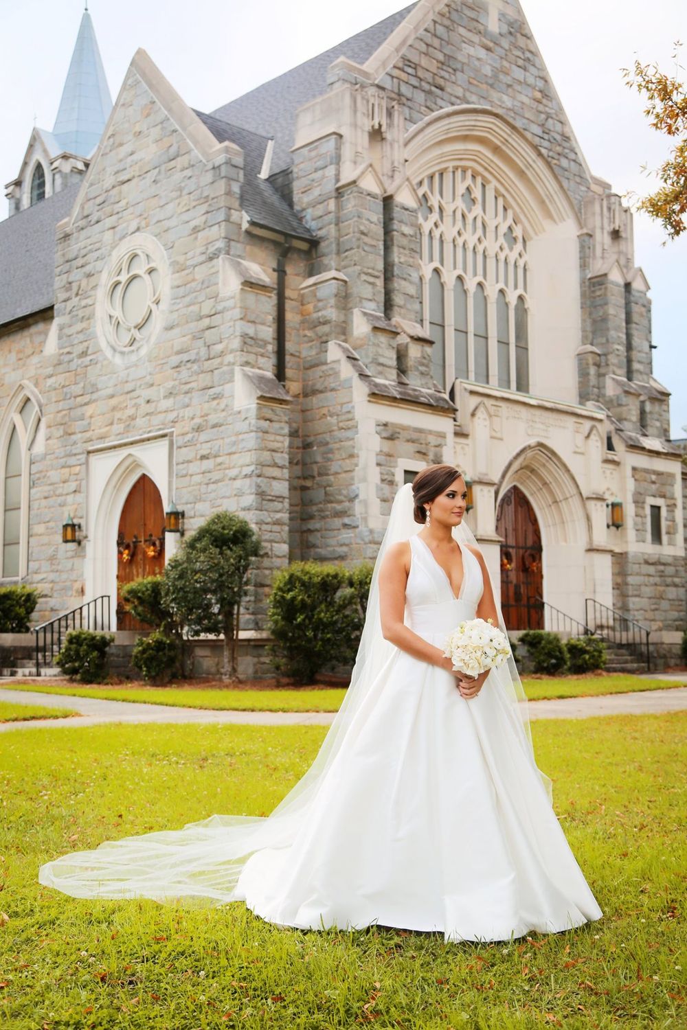 Beautiful wedding portrait in front of stone Gothic church with long cathedral veil.