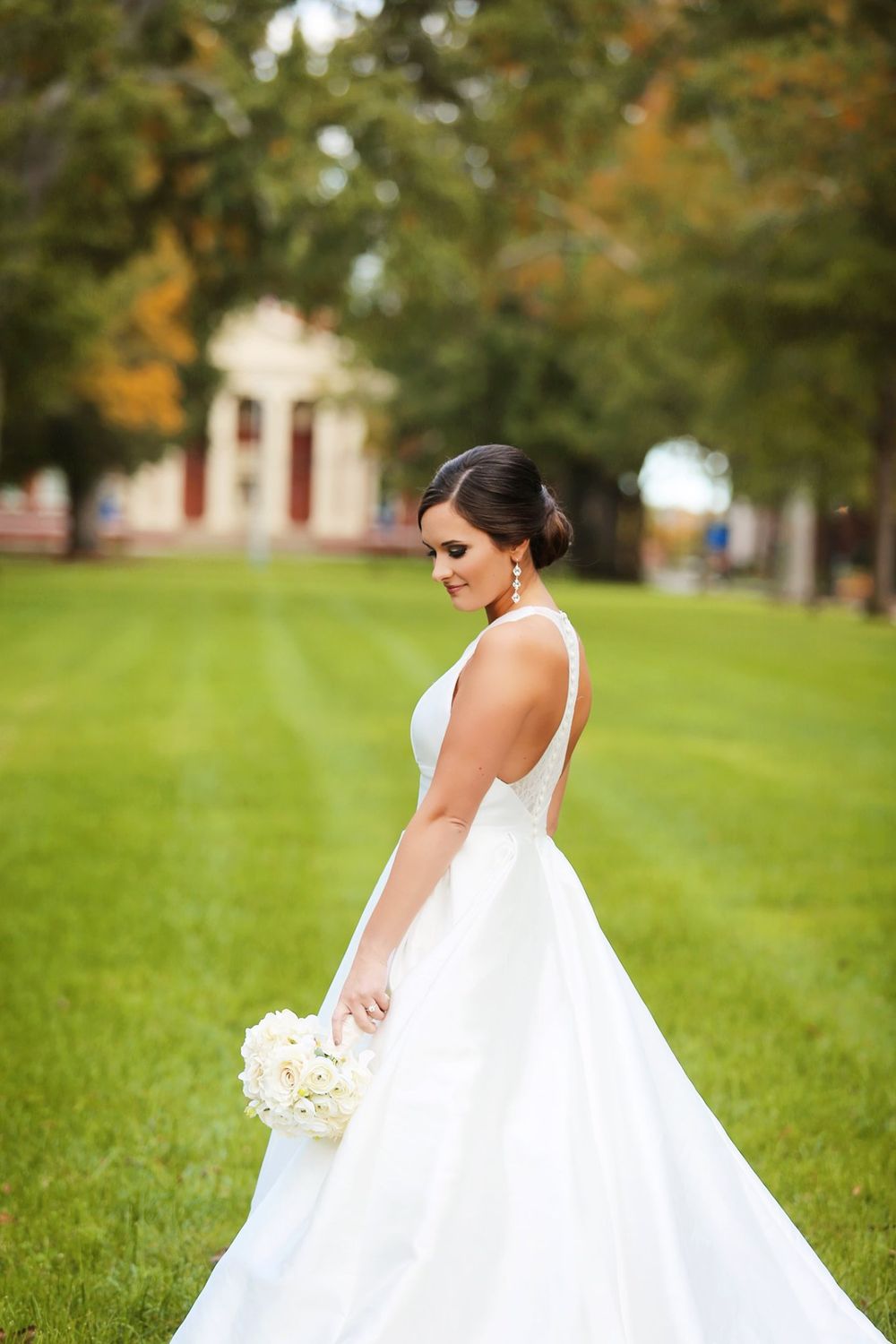 Elegant bridal portrait on manicured lawn with white bouquet.