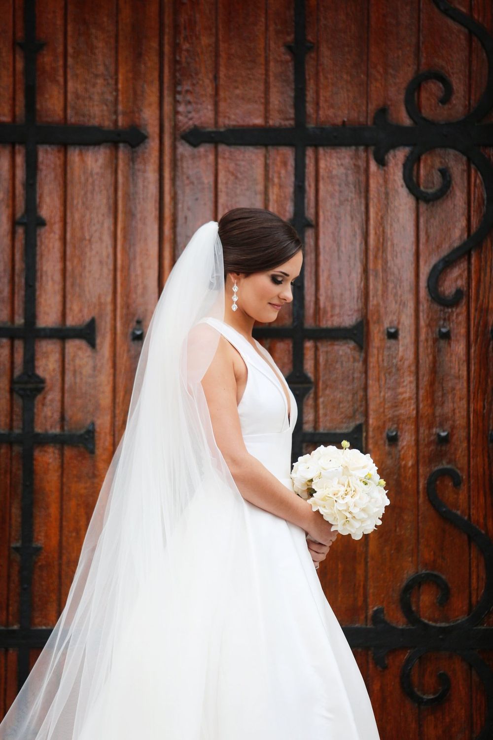 Classic bridal portrait against wooden door with ornate iron details.