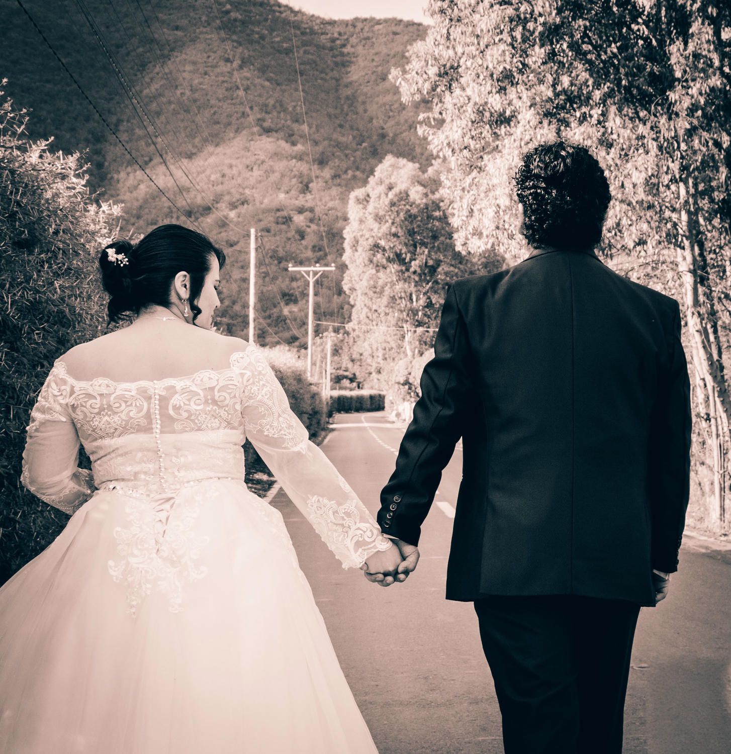 A black and white panoramic series showing the backs of a wedding couple walking outdoors.
