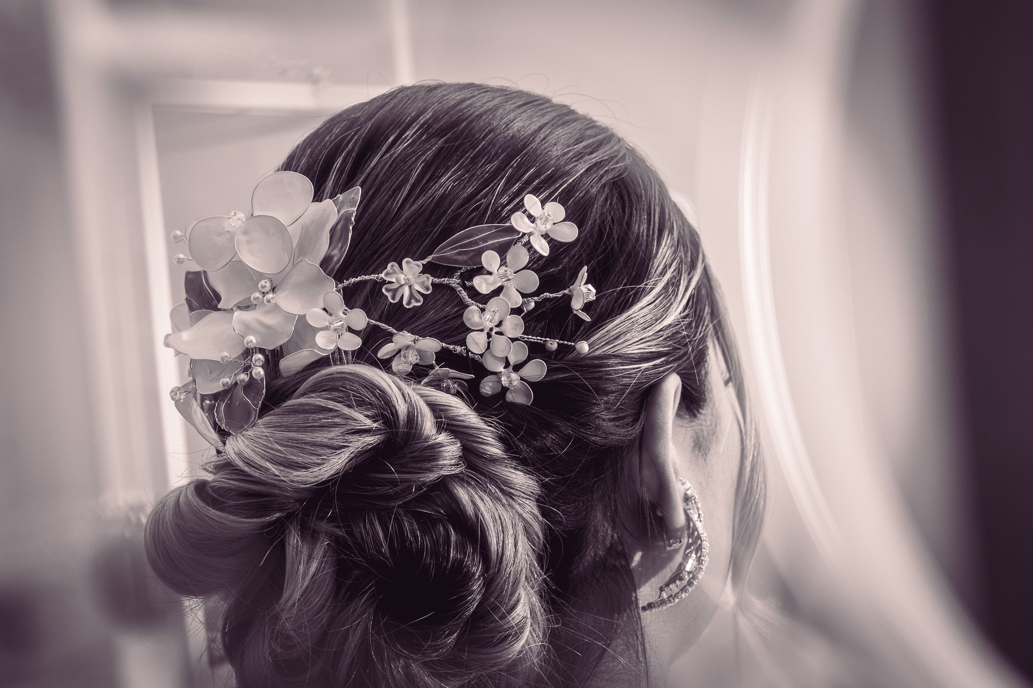 Peinado elegante de novia con accesorios florales fotografiado en blanco y negro.