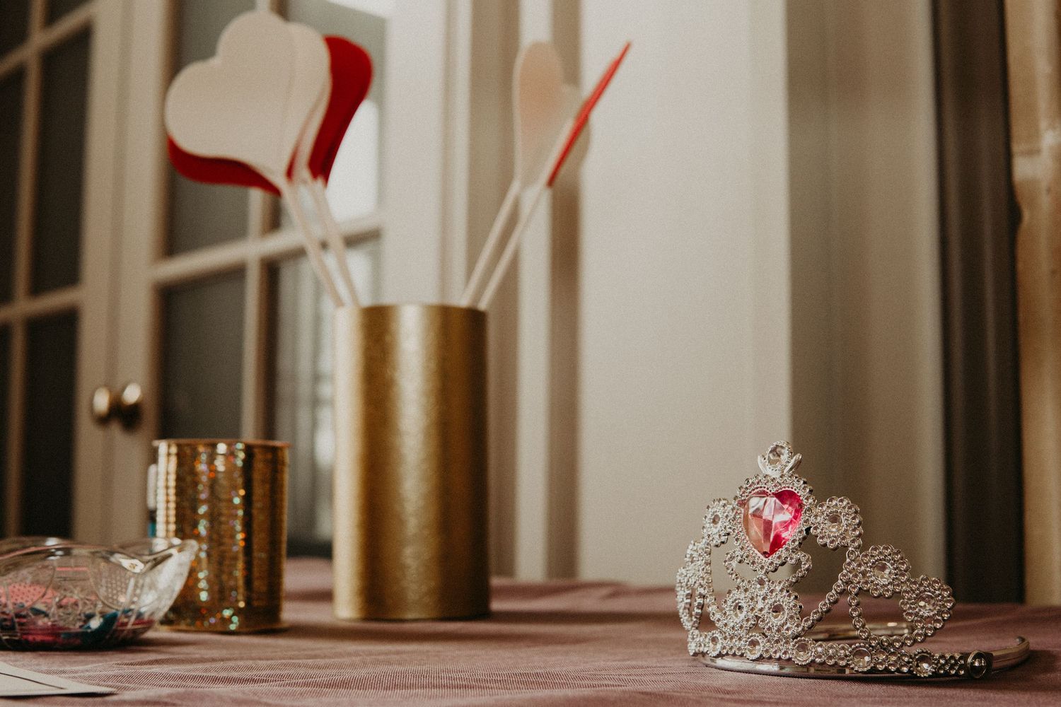 Decorative princess tiara and gold vase with red hearts on display.