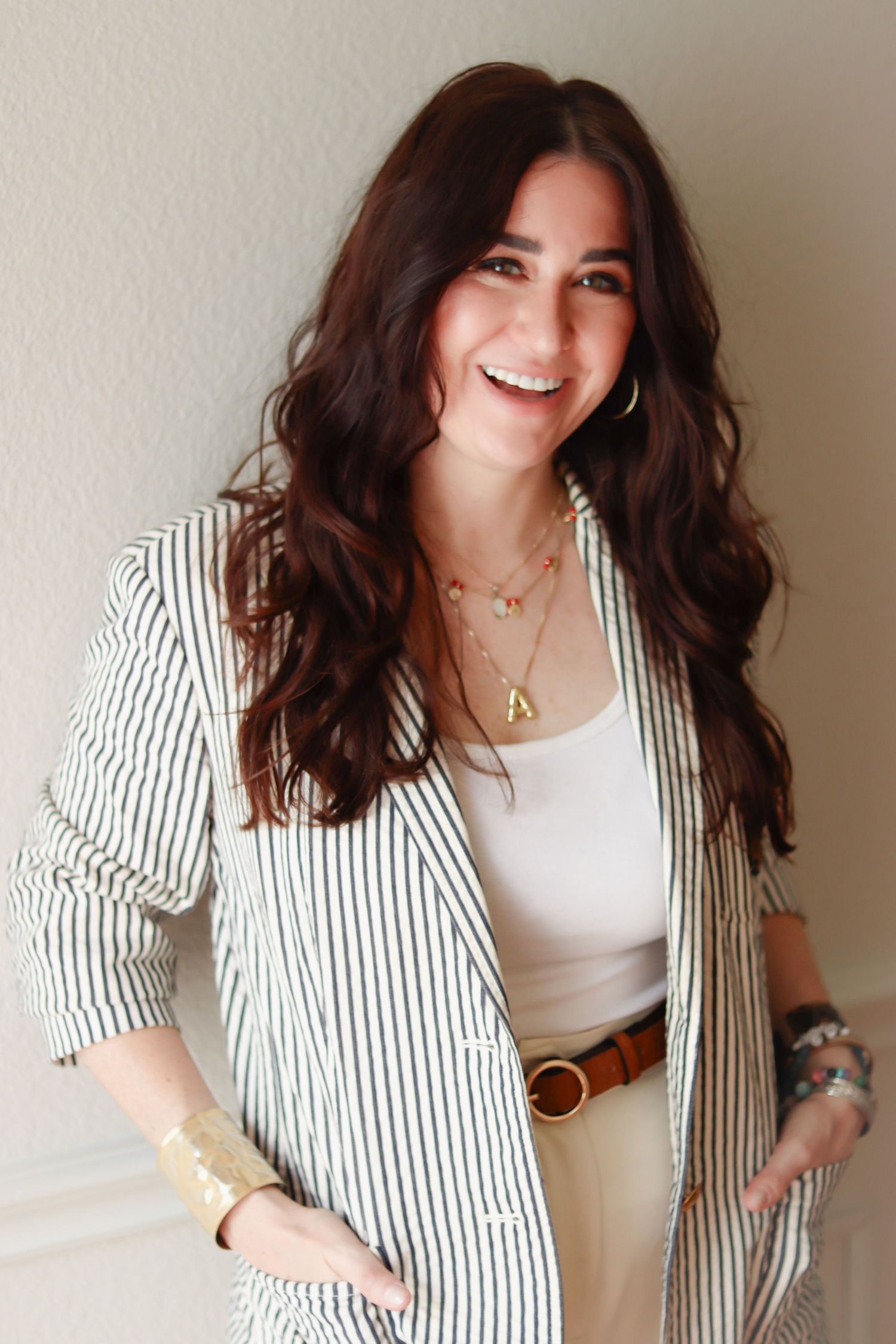 Professional portrait in striped blazer against neutral background with natural lighting.