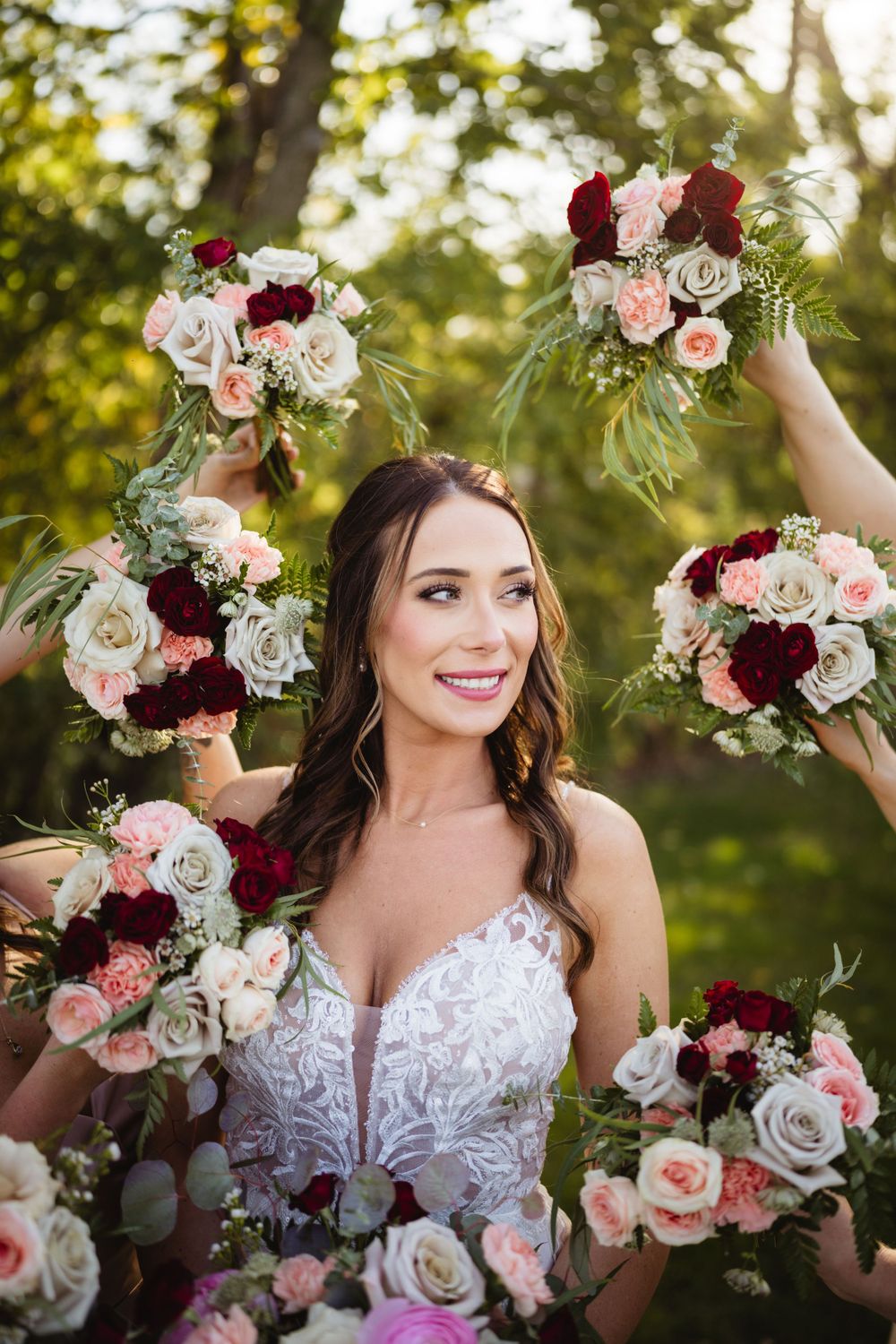 Multiple bouquets of burgundy and blush roses frame scene in golden sunlight.