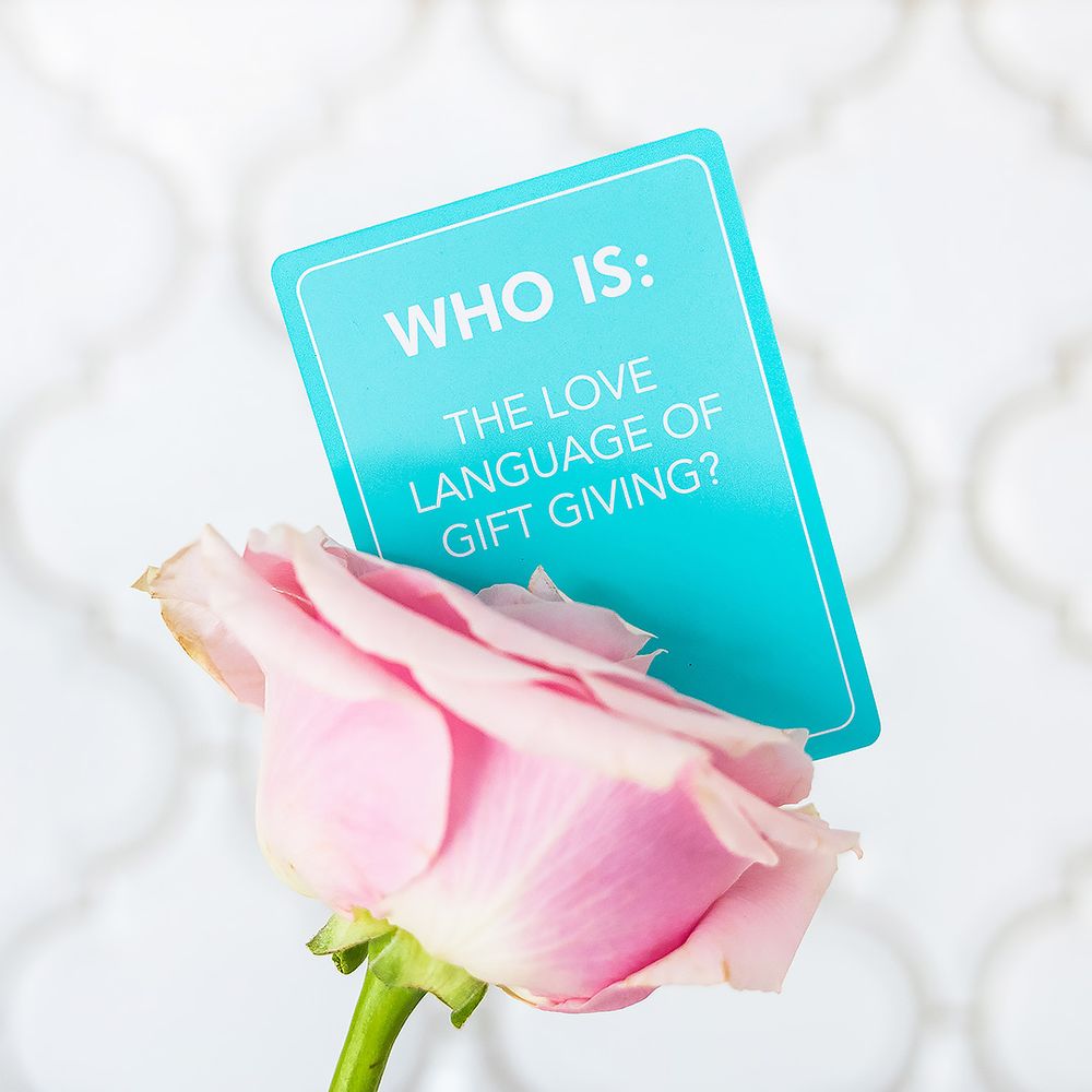Turquoise 'Who Is' card about love language with pink rose in soft focus.