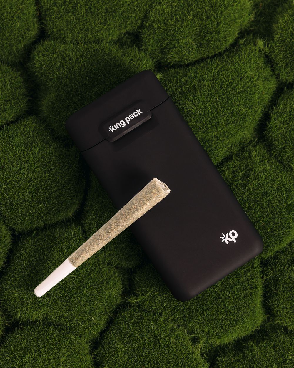 Black portable device case with pre-roll displayed on green textured background.