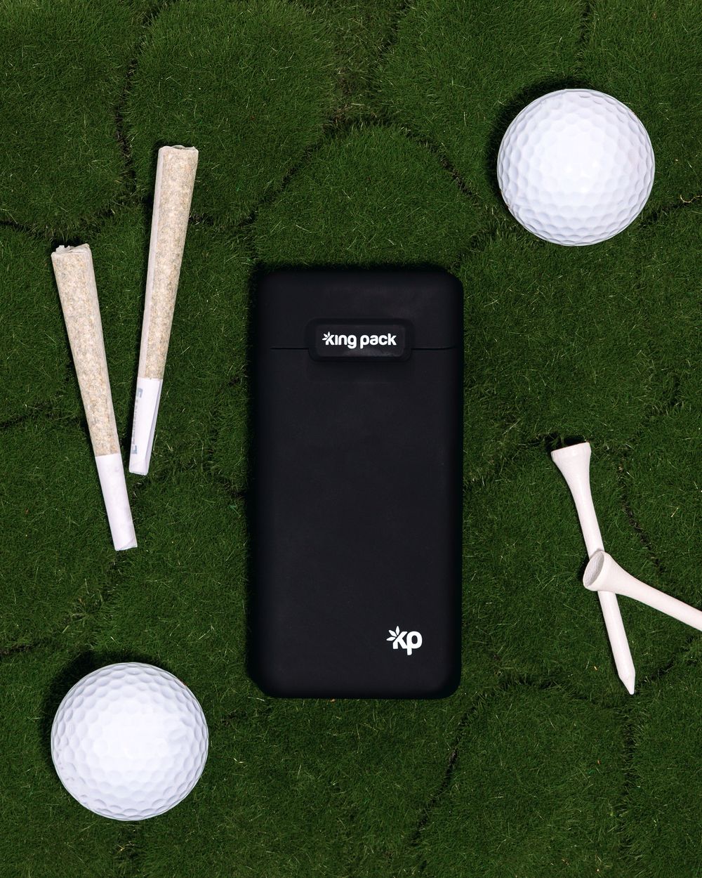 Black vape charging case displayed on golf green with golf balls and tees.