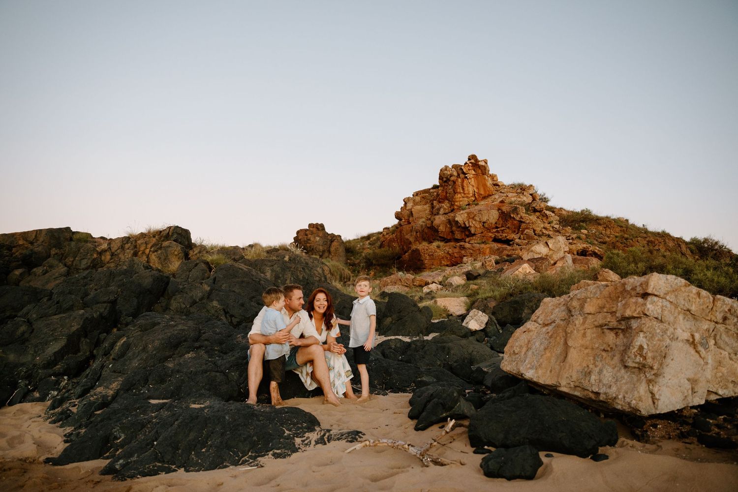 Family photography session on rocky coastal outcrop during golden hour in Wickham.