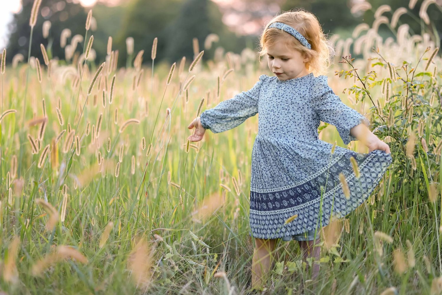 Girl twirls and walks through a field of tall grass