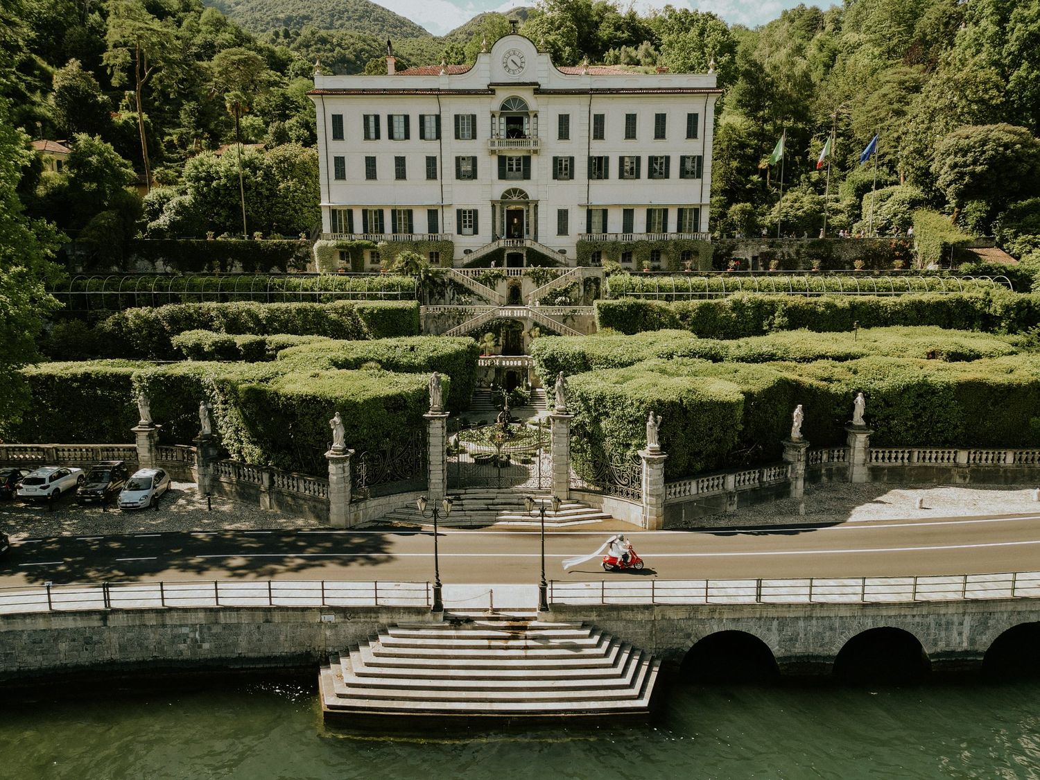 Elegant white villa with manicured gardens and grand staircase overlooking Lake Como in Italy.