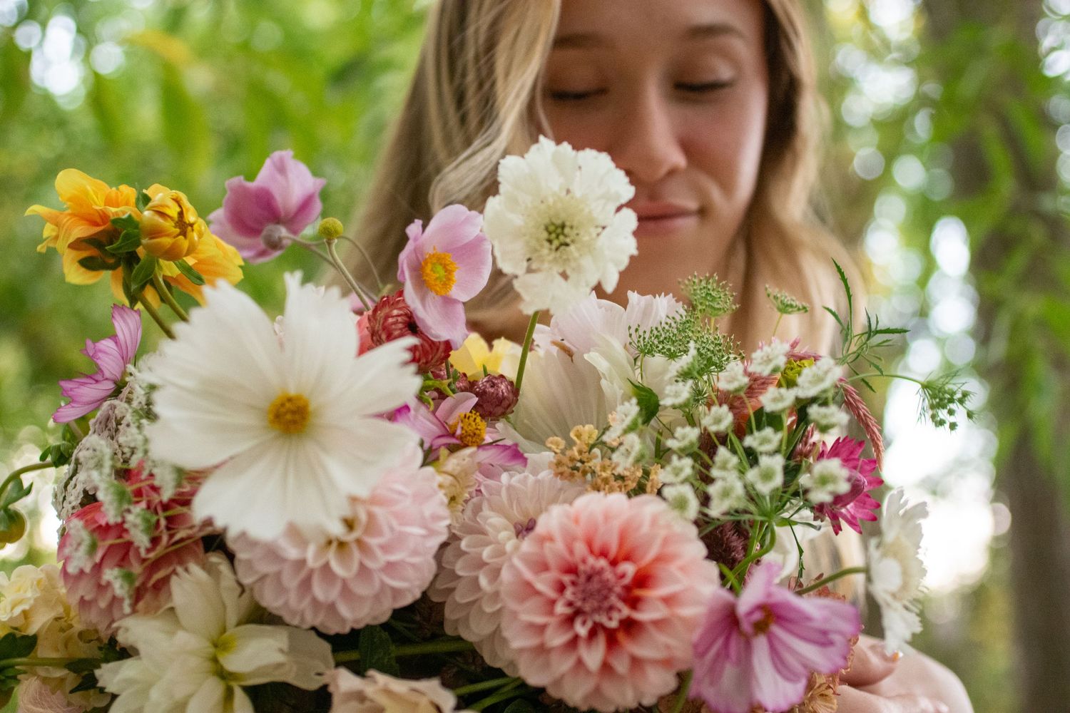 Woman looks down at bouquet of pink and white flowers made by Utah floral company pomegranatepom.florals.