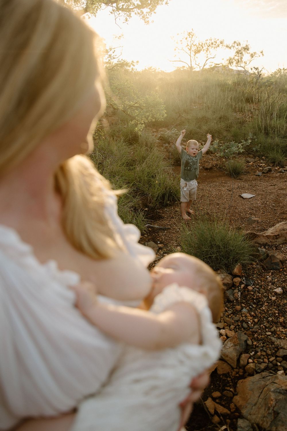 Family enjoying golden hour outdoors on a nature trail with sunlight streaming through trees and rocks.