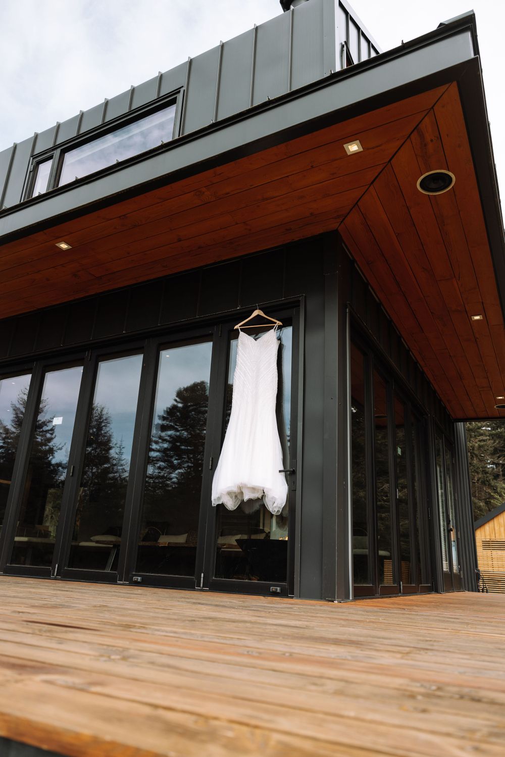 Modern building exterior with a white wedding dress hanging against dark metal and wood architecture.