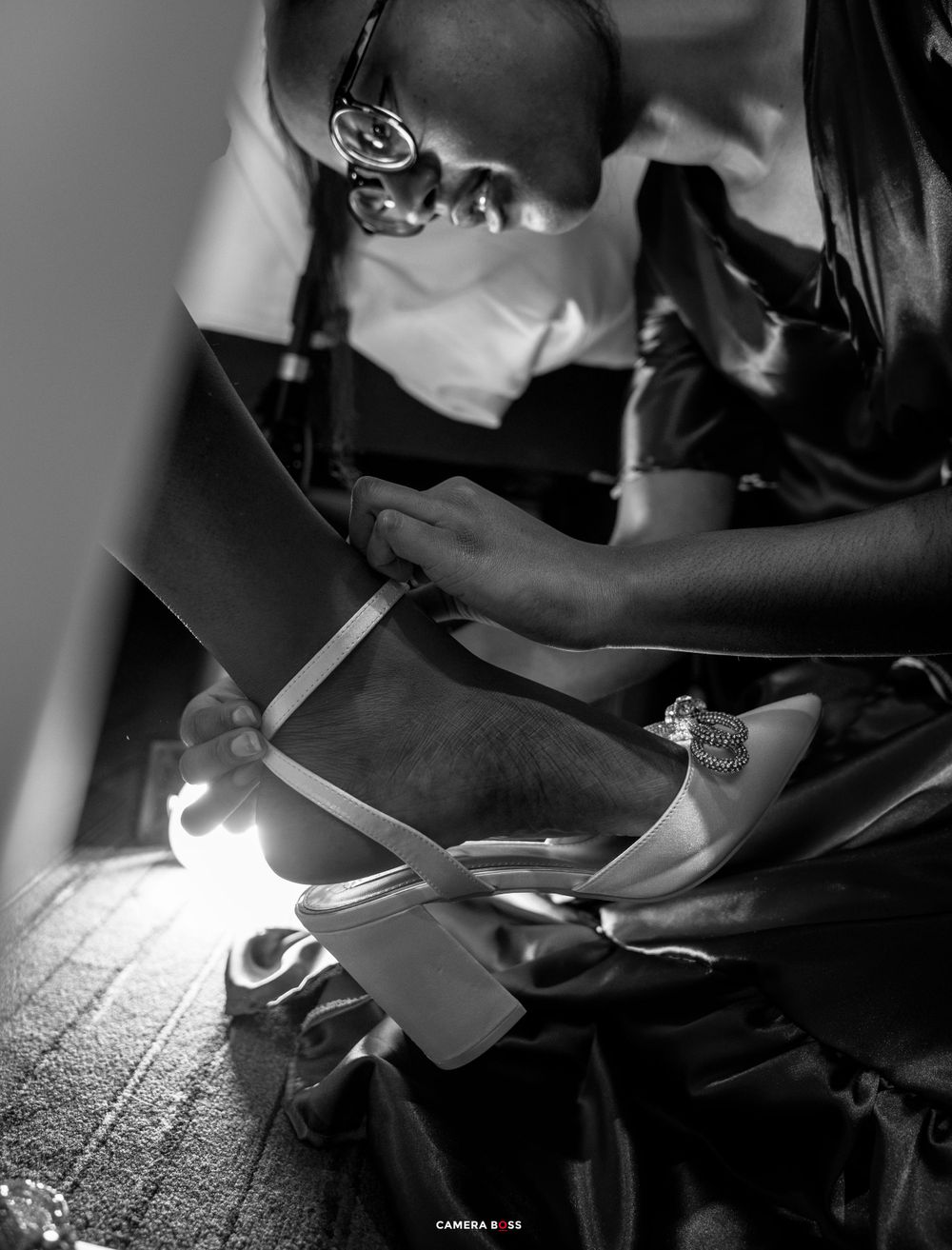A healthcare professional in mask and scrubs examines patient notes in dramatic black and white lighting.
