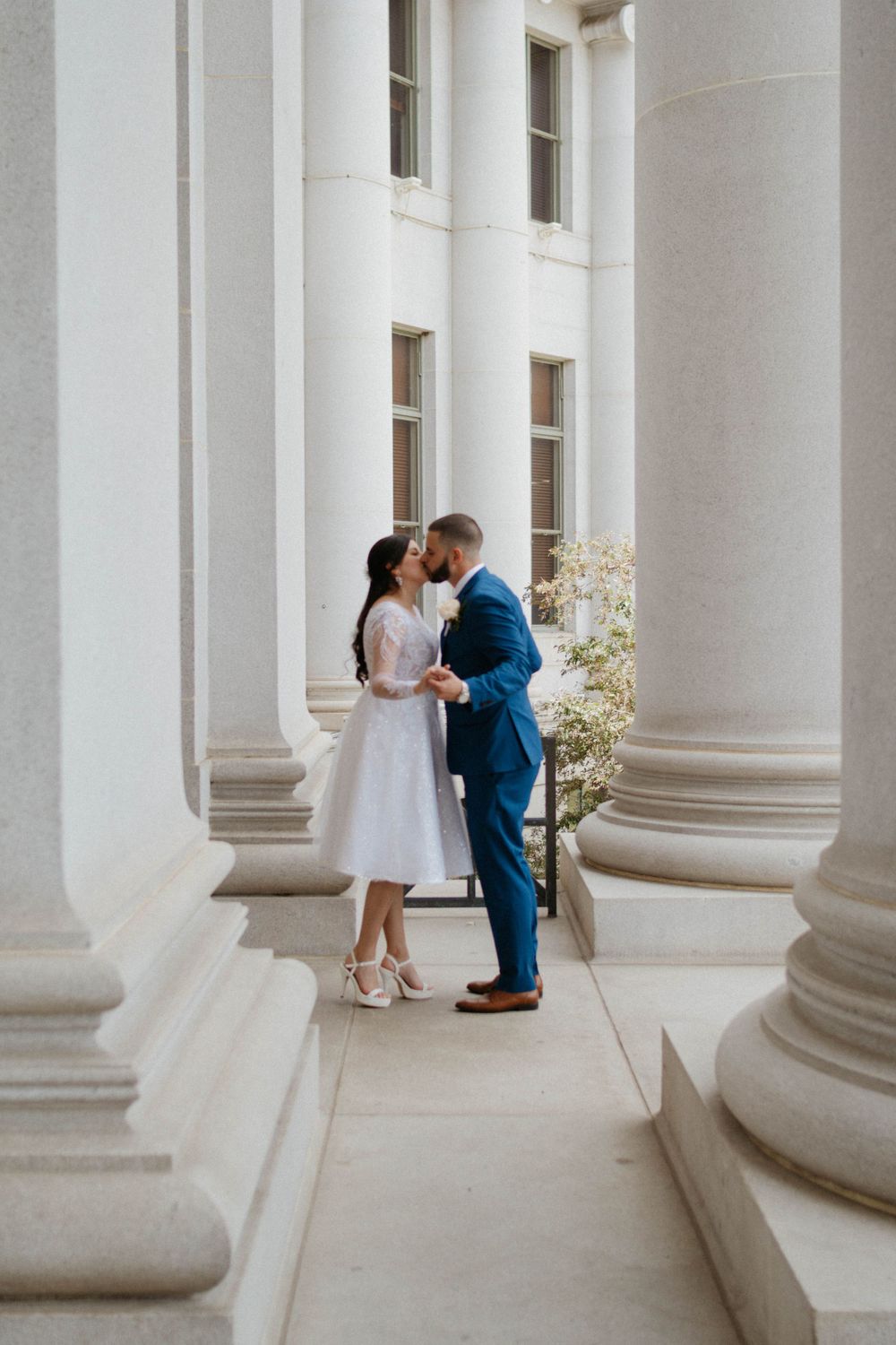 A romantic,  elopement couple in Denver, Colorado in elegant white stone columns of a grand court house. Timeless, photoshoot