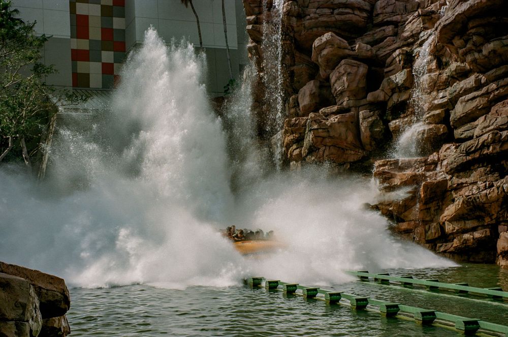 An exciting water ride creating a massive splash through rocky terrain at a theme park.